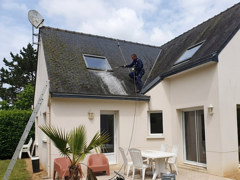 Artisan couvreur appliquant un traitement de démoussage et hydrofuge sur un toit pavillonnaire